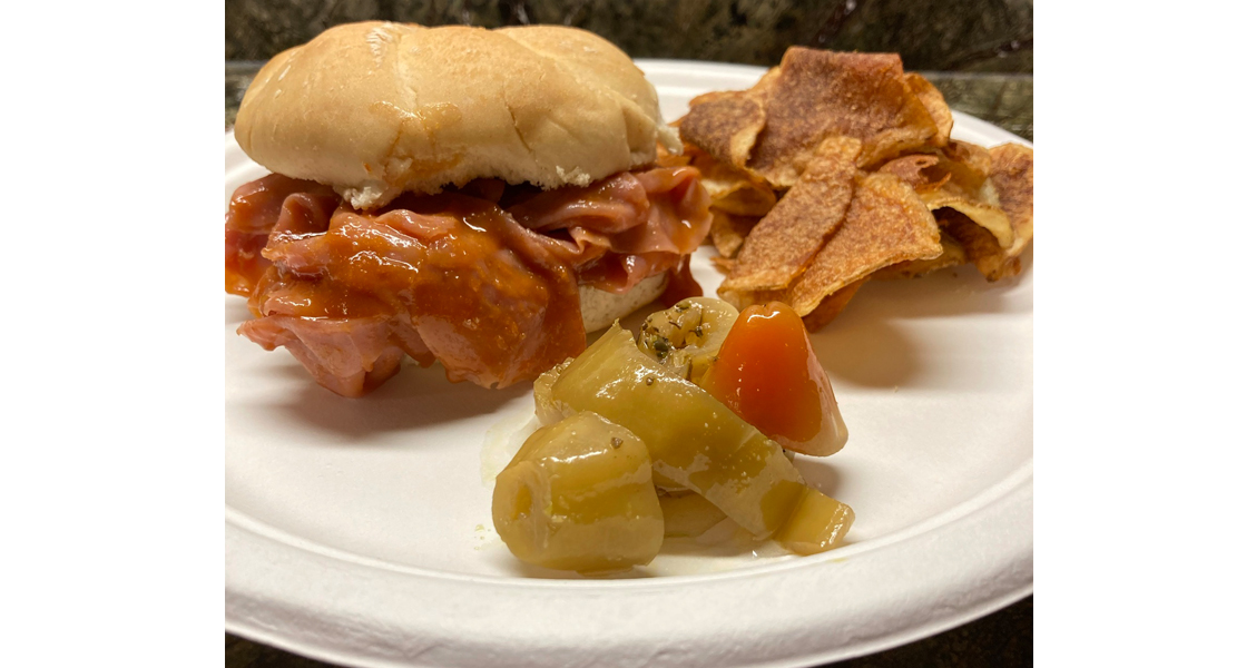 Isalys Ham BBQ on a roll with pickle and potato chips